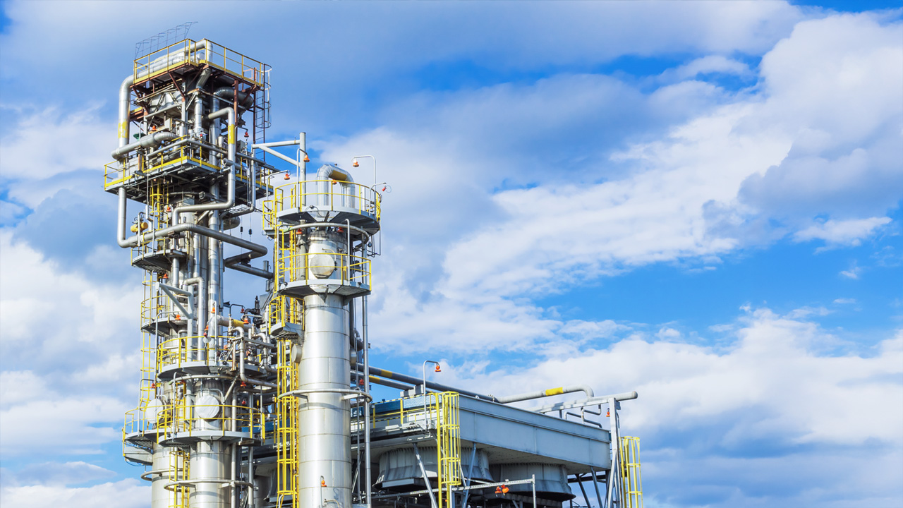 Two absorption columns stand at the gas processing plant against the blue sky.